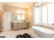 Bathroom featuring a freestanding tub, large window with shutters, chandelier and undermount sink at 1875 Highway 142 E, Covington, GA 30014
