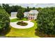 Elegant white home featuring a circular driveway, beautiful landscaping, and a separate garage at 1875 Highway 142 E, Covington, GA 30014
