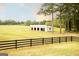 Expansive green field with a white barn featuring multiple bays, and black fencing for a serene and country lifestyle at 1875 Highway 142 E, Covington, GA 30014