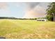 Sprawling green field with a white barn featuring multiple bays, perfect for equestrian enthusiasts and country living at 1875 Highway 142 E, Covington, GA 30014
