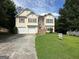 Two-story home with a two-car garage and manicured front lawn surrounded by mature trees at 3393 Madison Farm Way, Snellville, GA 30039