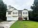Two-story home with a two-car garage and manicured front lawn surrounded by mature trees at 3393 Madison Farm Way, Snellville, GA 30039