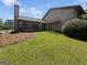 A spacious backyard featuring a covered patio area, lawn, and wooded perimeter in a quiet neighborhood at 1084 Village Rd, Stone Mountain, GA 30088