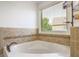 Close-up of bathtub featuring tile surround, bronze faucet, and window with blinds at 6510 Bentley Ridge Dr, Cumming, GA 30040