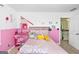 Whimsical bedroom featuring pink walls, plush décor and an open door to the hallway with carpeted stairs at 6510 Bentley Ridge Dr, Cumming, GA 30040