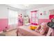 Charming bedroom with pink accents, two windows, and a full-size bed with a variety of stuffed animals at 6510 Bentley Ridge Dr, Cumming, GA 30040