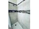 Shower stall features neutral tilework with accent tiles and a mounted shower caddy for storage at 2606 Ramblewood Ct, Acworth, GA 30102