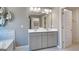 A stylish bathroom with a large mirror, double sinks, gray tiled floor, and natural light at 1678 Lacebark Elm Way, Lawrenceville, GA 30045