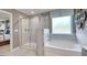 A luxurious bathroom featuring a separate glass shower, soaking tub, and decorative mirror at 1678 Lacebark Elm Way, Lawrenceville, GA 30045