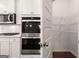 Modern white kitchen featuring stainless steel appliances, double ovens, and a convenient walk-in pantry at 1678 Lacebark Elm Way, Lawrenceville, GA 30045