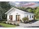 Charming exterior of white home with black trim, outdoor patio, and landscaped front yard during the day at 17 Cheney St, East Point, GA 30344