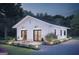 Charming exterior of white home with black trim, outdoor patio, and landscaped front yard at night at 17 Cheney St, East Point, GA 30344