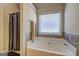 Bright bathroom showcasing a soaking tub with tiled surround and window at 1223 Hartwell Rd, Locust Grove, GA 30248