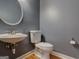 A half bathroom features a pedestal sink, a round mirror, and a toilet at 2560 Almont Way, Roswell, GA 30076