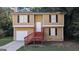 Inviting two-story home featuring tan siding, black shutters, and stairs to a covered front porch at 5300 Forest Downs Ln, Atlanta, GA 30349