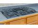 Close-up of a modern gas cooktop with black surface and wooden cabinets at 4424 Bellwood Cir, Atlanta, GA 30349