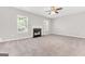 Living room with a decorative fireplace, carpet flooring, neutral walls, and many windows for natural light at 655 Wildboar Ct, Fairburn, GA 30213