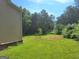 Lush backyard featuring green grass, a young tree, and wooded boundary at 200 Parker Dr, Mcdonough, GA 30253