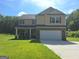 Two-story home with brick and siding, a two-car garage, and a well-manicured lawn on a sunny day at 200 Parker Dr, Mcdonough, GA 30253