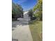 Exterior view of the home's driveway and garage with a manicured lawn and mature trees under a bright blue sky at 200 Eagle Glen Ct, Woodstock, GA 30189