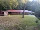 A single-story brick home has a bright red metal roof, a small tree, and a covered carport at 10108 Lakeview Sw Dr, Covington, GA 30014