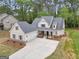 Aerial view of the white farmhouse exterior with a spacious three car garage and long concrete driveway at 241 Ben Horton Dr, Mcdonough, GA 30253