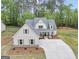 Aerial view of a white farmhouse with gray roof, a spacious three car garage and large concrete driveway at 241 Ben Horton Dr, Mcdonough, GA 30253