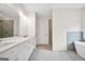 Bright bathroom featuring double vanity with quartz countertop, modern fixtures, shower, and soaking tub at 241 Ben Horton Dr, Mcdonough, GA 30253