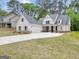 Beautiful white farmhouse exterior with a spacious three car garage and a long driveway at 241 Ben Horton Dr, Mcdonough, GA 30253