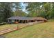 Exterior view of the home surrounded by lush trees and featuring a split-rail fence at 1973 Glendale Dr, Decatur, GA 30032