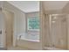 Bright bathroom featuring a large tub under a window and a glass enclosed shower at 22 Agean Way, Whitesburg, GA 30185