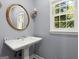 Stylish powder room with pedestal sink, updated fixtures, and natural light from window at 7300 Chattahoochee Bluff Dr, Sandy Springs, GA 30350