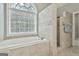 Bright bathroom featuring a soaking tub, tiled shower, and large arched window at 684 Brooks Woolsey Rd, Brooks, GA 30205