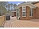 A wooden deck featuring a grill and a brick exterior with large windows surrounded by trees at 684 Brooks Woolsey Rd, Brooks, GA 30205