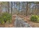 Charming gravel driveway winds through a picturesque wooded landscape, creating a tranquil entrance to the home at 684 Brooks Woolsey Rd, Brooks, GA 30205