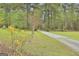 Picturesque view of a long gravel driveway surrounded by mature trees and vibrant flowering bushes at 684 Brooks Woolsey Rd, Brooks, GA 30205