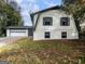 Two-story home with white painted brick, a gray trim, a two-car garage and an attached door on a tree-filled lot at 4239 Newcomb Rd, Decatur, GA 30034