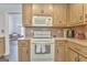 Traditional kitchen featuring wood cabinets, warm countertops, and white appliances at 408 Gray Fox Dr, Canton, GA 30114