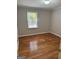 Cozy bedroom with neutral paint, wood floor, and a bright window overlooking the yard at 7193 Tara Dr, Villa Rica, GA 30180