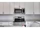 Modern kitchen with stainless steel appliances, white cabinets, subway tile backsplash, and granite countertops at 734 W College St, Bowdon, GA 30108