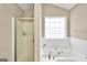 Relaxing bathroom features a garden tub, glass door shower, and bright window for natural light at 130 Nicki Ct, Hampton, GA 30228