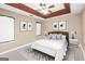Stylish main bedroom features a tray ceiling, ceiling fan, neutral walls, and decorative art at 130 Nicki Ct, Hampton, GA 30228