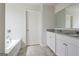 Bathroom featuring a double vanity with granite counters, tile flooring, and a separate soaking tub at 4390 Merrigold Way, Fairburn, GA 30213