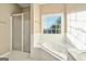 Main bathroom featuring a soaking tub, shower, and a large window at 625 Aya Cir, Loganville, GA 30052