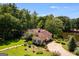 Aerial view of a beautiful property with a house, lush lawn, mature trees, and a serene pond at 50 Persian Pl, Whitesburg, GA 30185