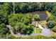 Aerial view showcases the home on a wooded lot with a private pond, blending privacy and scenery at 50 Persian Pl, Whitesburg, GA 30185