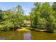 A scenic view showcases a home nestled among mature trees beside a serene pond at 50 Persian Pl, Whitesburg, GA 30185