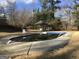 Backyard swimming pool with concrete deck and gazebo in the background surrounded by tall trees at 55 Gill Ln, Stockbridge, GA 30281