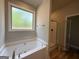 Bathroom featuring a shower with glass door and a separate soaking tub with window at 1547 South Bethany Rd, Locust Grove, GA 30248