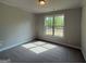 Carpeted bedroom featuring a neutral color palette and a large window overlooking trees at 1547 South Bethany Rd, Locust Grove, GA 30248